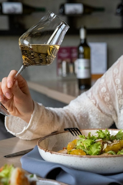 女の子はレストランで昼食を食べます 夕食は女の子が白ワインを飲みます ワインと一緒に食事をする