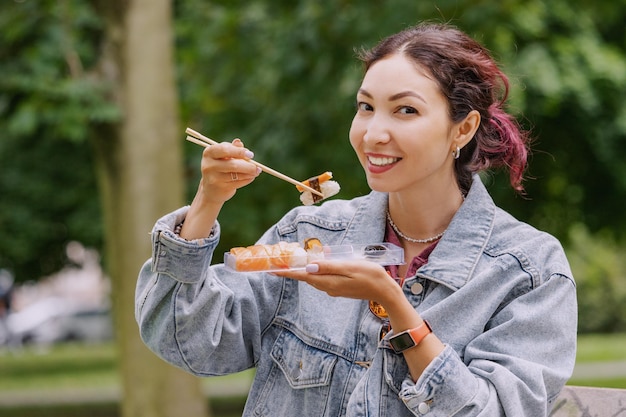 한 소녀는 근무일 요리와 다이어트 개념을 마친 후 공원에서 전통 일본 스시로 점심과 간식을 먹습니다.