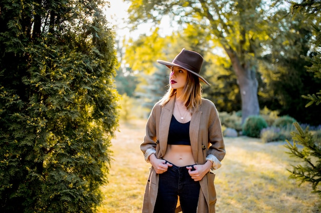 Girl in hat and clothes in a village garden in sunset time 