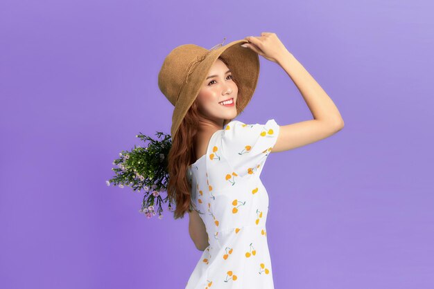 Girl in hat and flower dress poses with bouquet