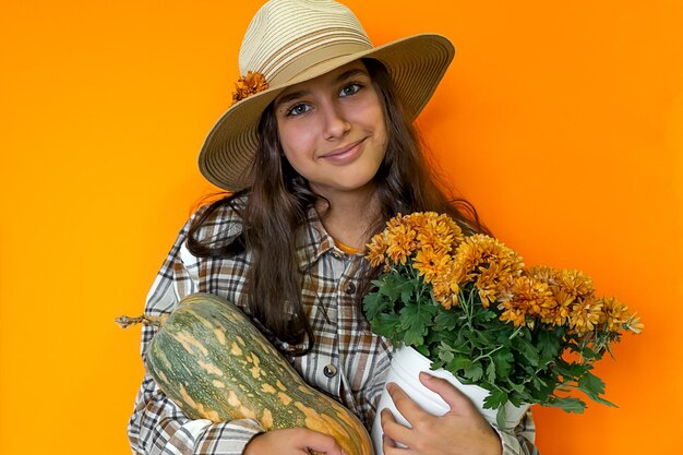 Girl in hat holds autumn harvest pumpkin