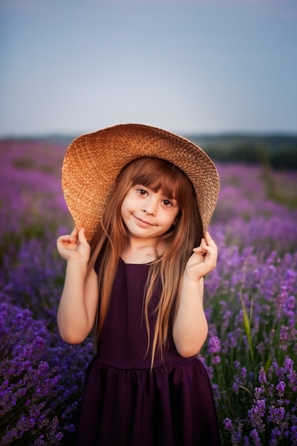 Girl in a hat in a lilac field of flowers