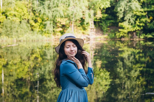 Девушка в шляпе отдыхает на осеннем озере на мосту
