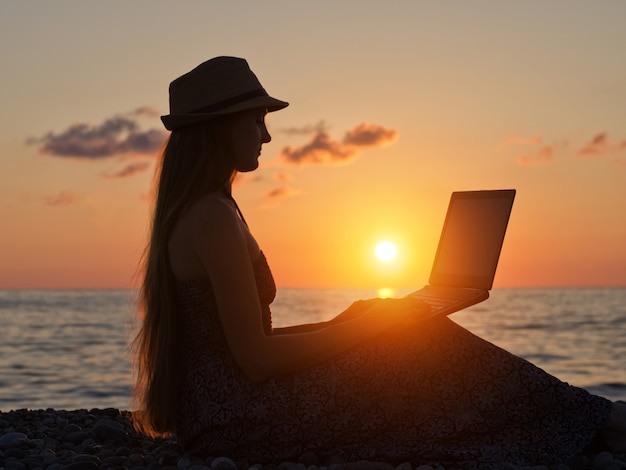 Photo girl in a hat sitting and working at his laptop