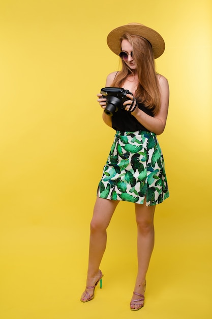 A girl in a hat and sunglasses with camera.