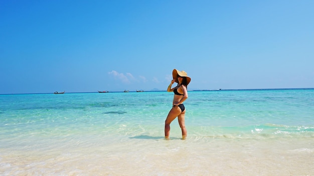 The girl in the hat and swimsuit on the beach