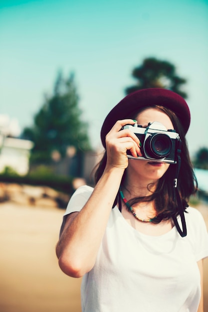 ヴィンテージカメラで写真を撮っている帽子の女の子