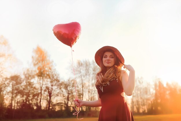 Una ragazza con un cappello durante una passeggiata nel parco una ragazza con un cesto cammina in autunno una ragazza cammina lungo la strada al tramontoxa