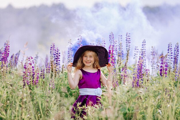 The girl in the hat walks in a field of lupines.