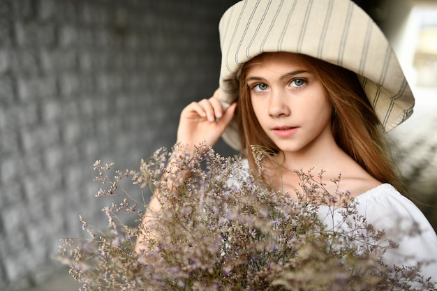 The girl in the hat with the flowers.