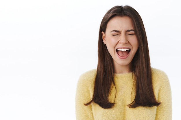 Girl having breakdown from too much stress, feel upset and uneasy screaming out loud with closed eyes, whining want someone pity her, standing lonely and sad over white wall