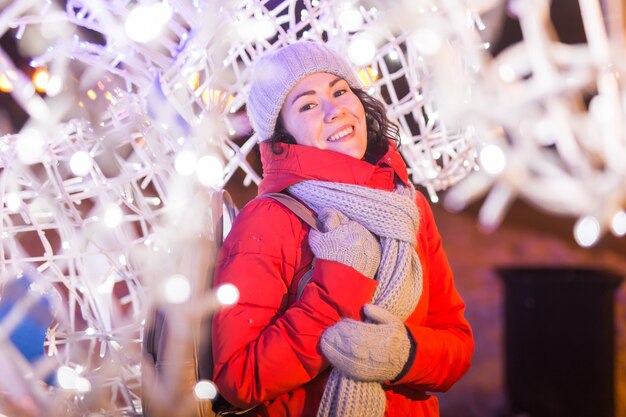 Девушка весело на рождественские украшения огни улице молодая счастливая улыбающаяся женщина, одетая в стильную