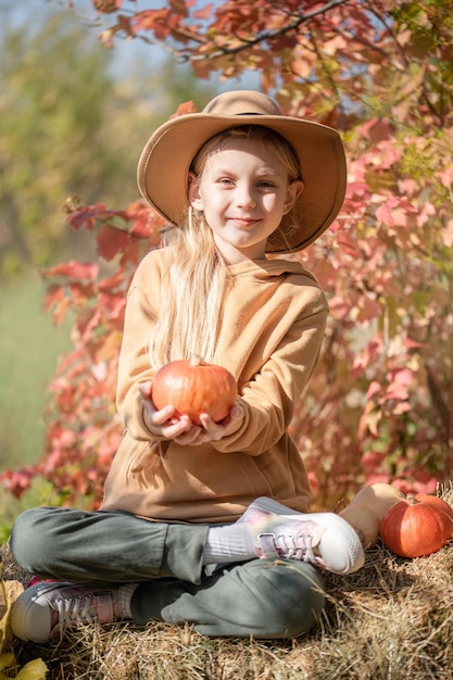 Girl in the hay with pumpkins