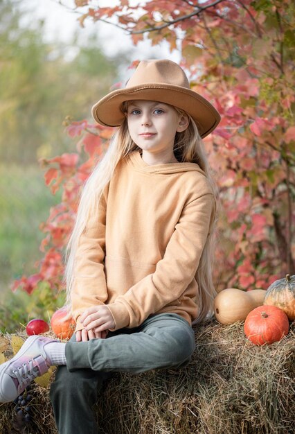 Girl in the hay with pumpkins