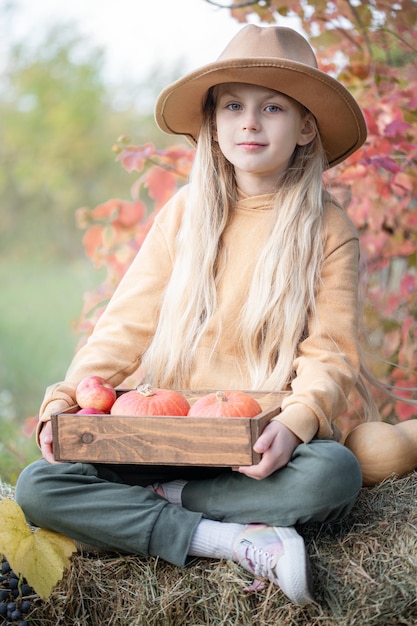 Girl in the hay with pumpkins