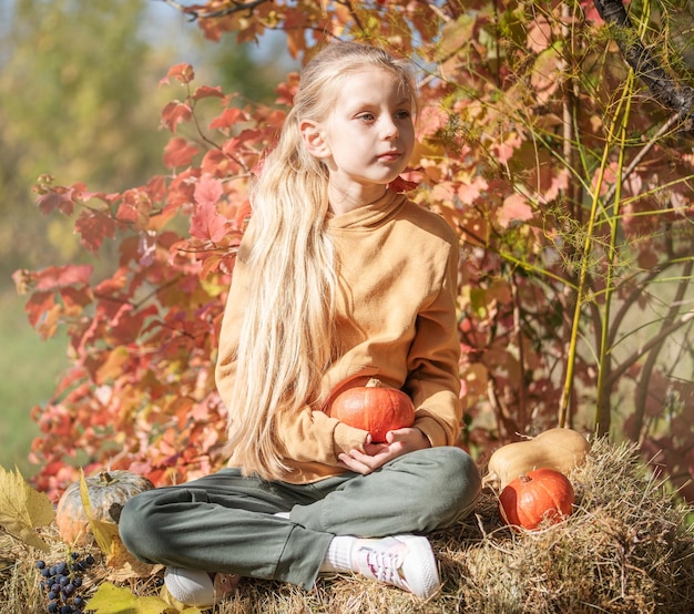 Girl in the hay with pumpkins