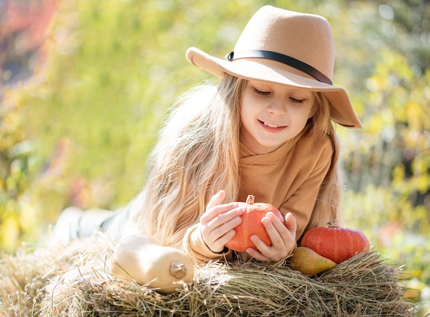 Girl in the hay with pumpkins