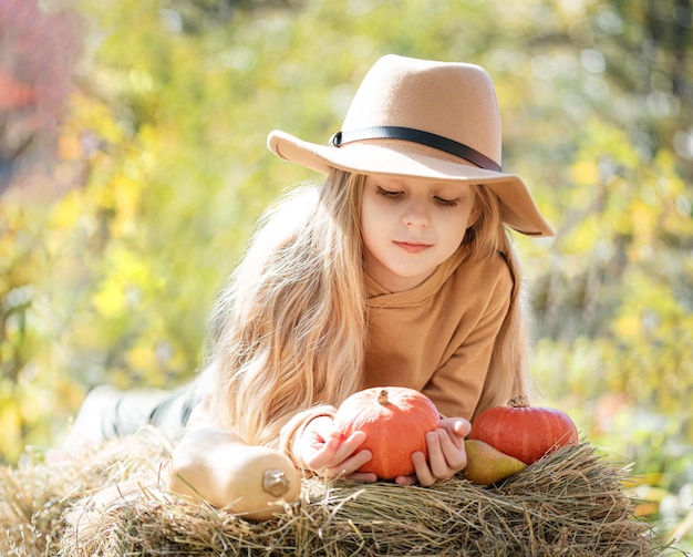 Girl in the hay with pumpkins