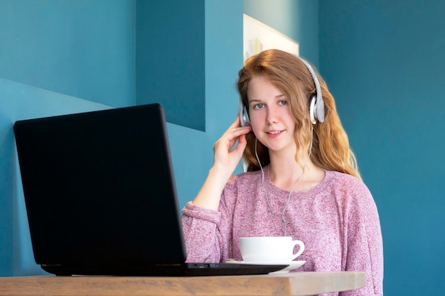 Girl in headphones communicates via video chat on a laptop.