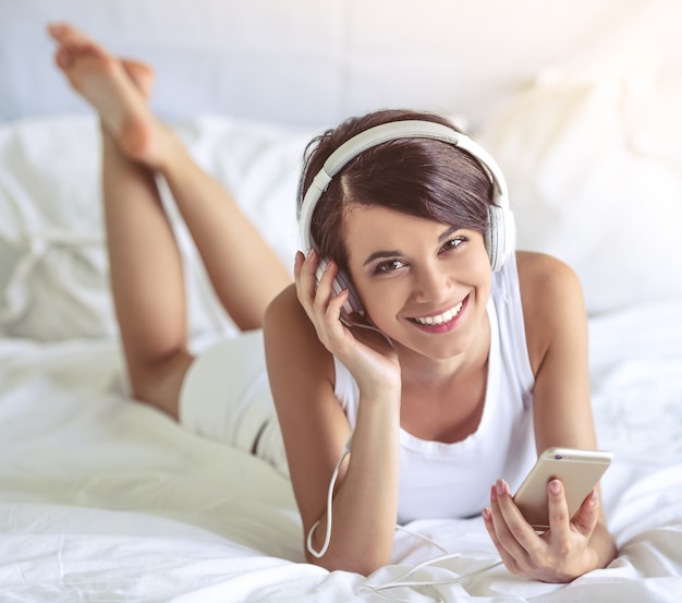 Girl in headphones is listening to music using a smartphone.