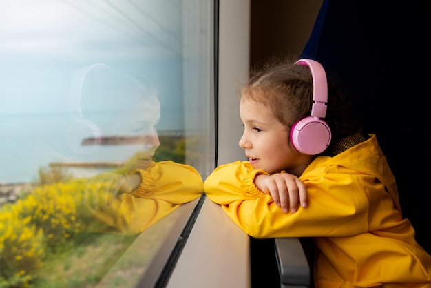 A girl in headphones on a train looks out the window Journey