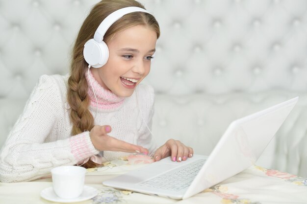 Girl in headphones using laptop at home