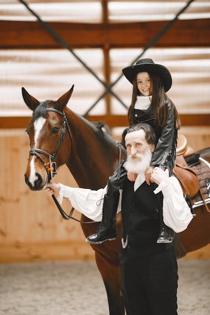 Girl in helmet Learning Horseback Riding. Instructor teaches little girl.