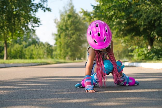 Foto una ragazza con un casco, guanti protettivi e ginocchiere è caduta mentre pattinava