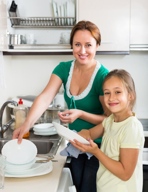 Girl helping mother washing dishes