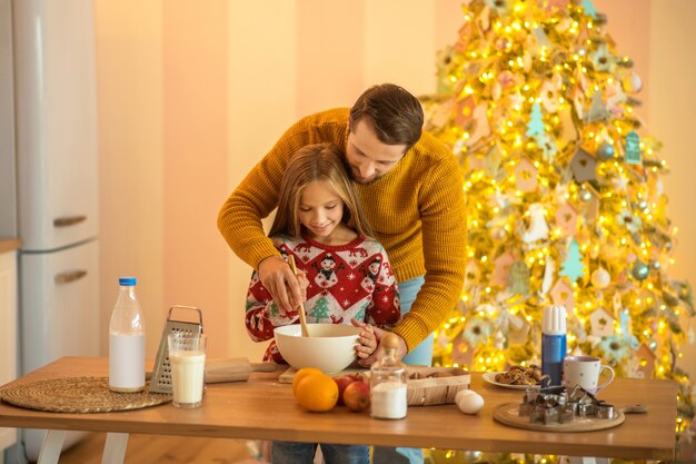 Girl and her dad stirring something in a bowl