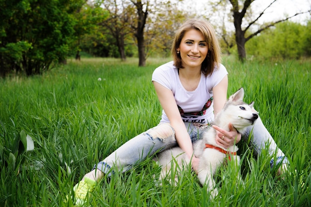 公園を歩いている少女と彼女の犬のハスキー