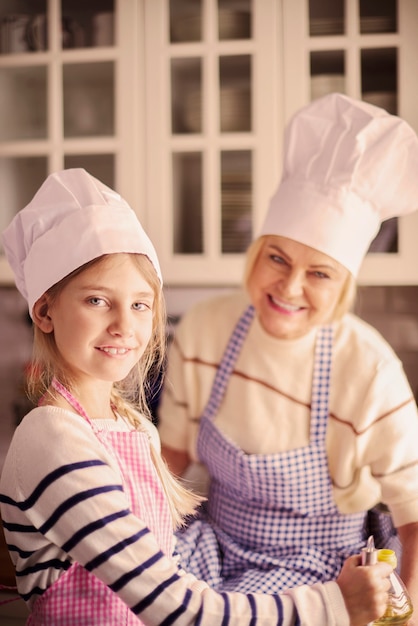 Girl and her grandmother wearing chefs hat