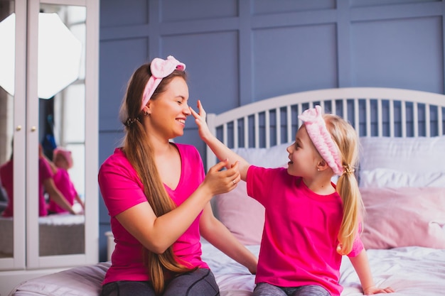 Girl and her mom sitting on the bed and make face care selfcare at lockdown