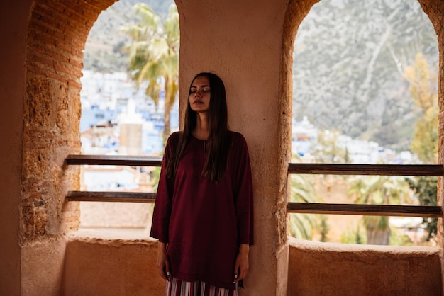 Girl hid in a wall between the windows of an old castle in the blue city of morocco