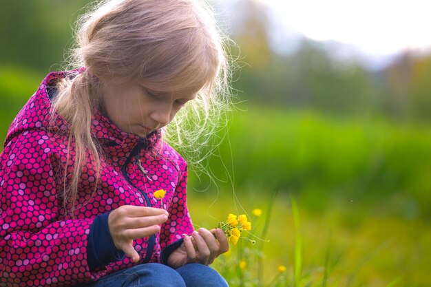 牧草地の草の上に座って夕日を楽しむ女の子のハイカー