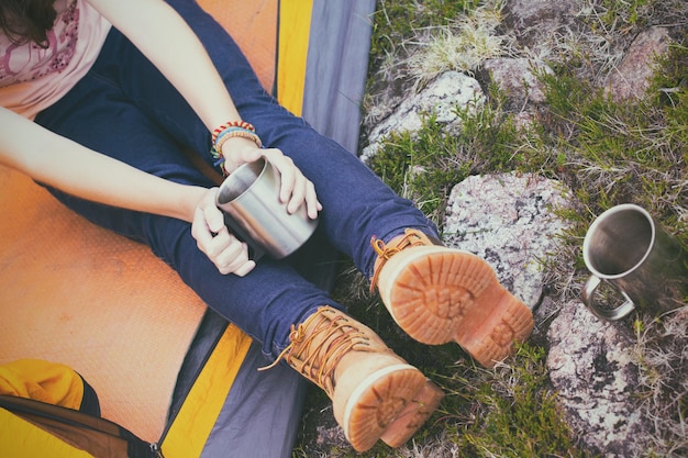 Девушка-туристка в палатке и держит чашку горы на заднем плане
