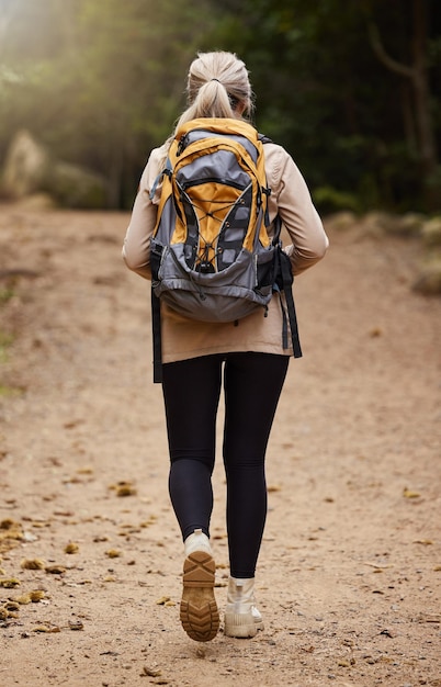 Girl hiking back view or woman in nature forest or wilderness for a trekking adventure Freedom backpack healthy female hiker walking in a natural park or woods for exercise or wellness on holiday