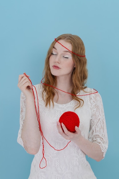 Girl hold a red thread knot Portrait on blue