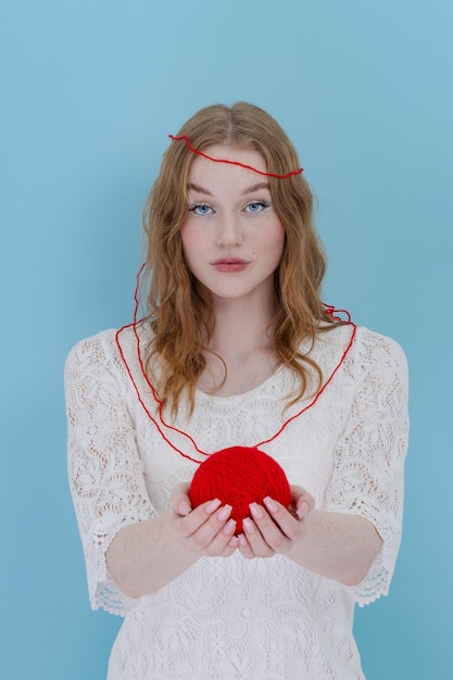 Girl hold a red thread knot Portrait on blue