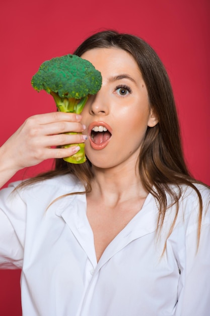 Девушка держит овощ Органическое питание Женщина держит брокколи Здоровые вегетарианские рецепты