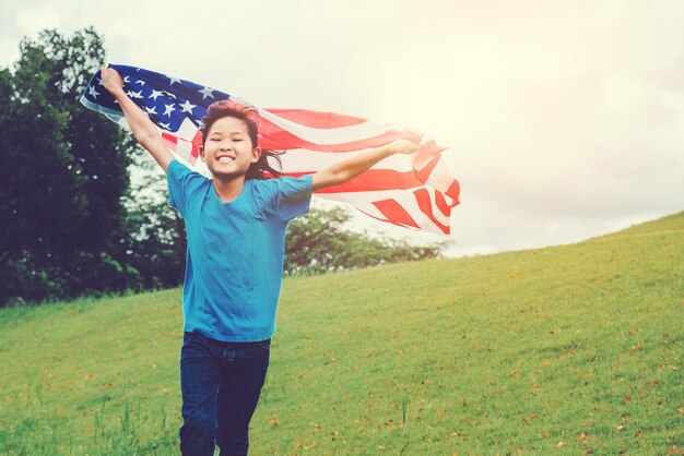 Photo girl holding american flag while running on field