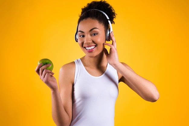 Girl holding an apple in her hand and listening to music