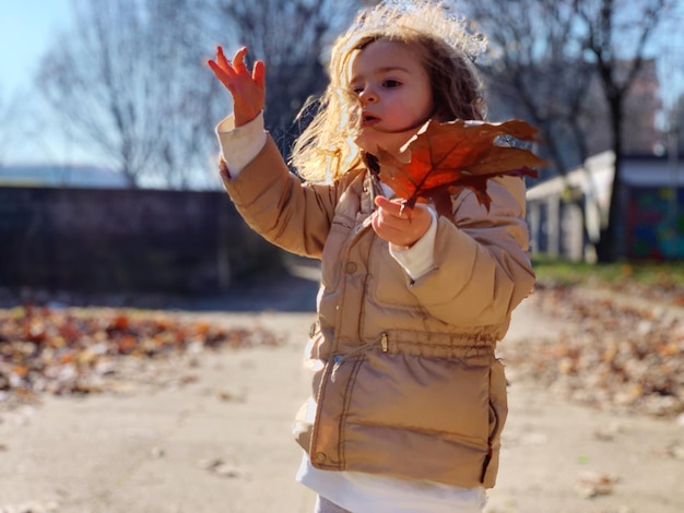 Foto ragazza con una foglia d'autunno in piedi sul campo