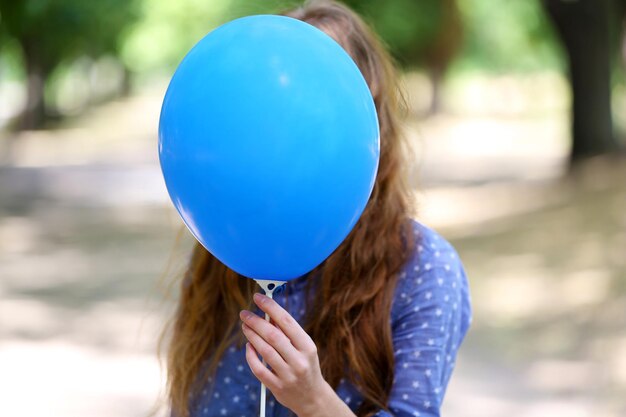 Photo girl holding balloon near face