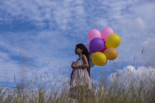 Photo girl holding balloons on land against sky