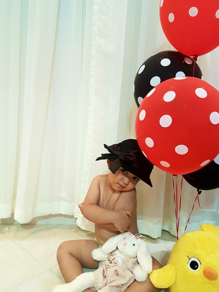 Photo girl holding balloons while standing by curtain at home