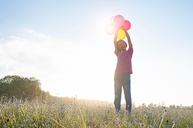 Girl holding balloons while standing on plants against sky