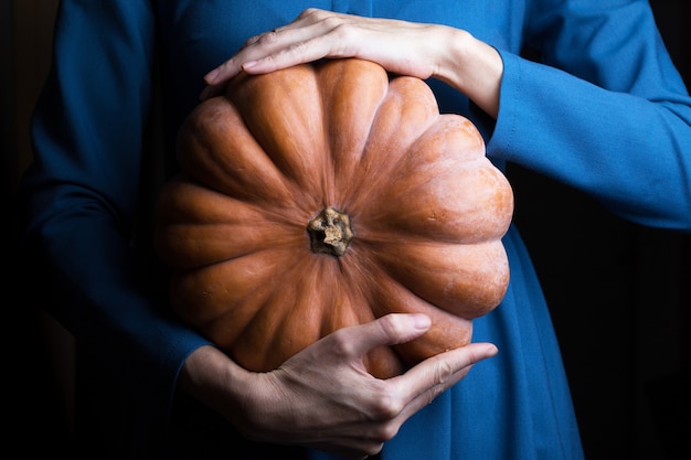 Girl holding beautiful aesthetic pumpkin on a black background