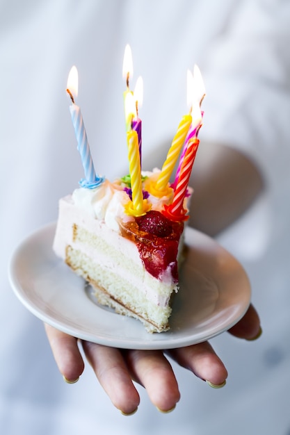 Girl holding beautiful appetizing birthday cake with many candles. Closeup.