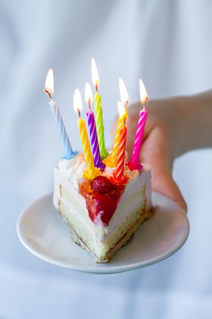 Girl holding beautiful appetizing birthday cake with many candles. Closeup.